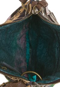 Inuti en handväska med mönster, förställd med en mörk teal-fodring, bronzefärgad dragkedja och guldfärgade detaljer. Innehåller texturerade material och livliga färger.