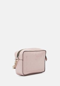 Mała kwadratowa torebka na ramię w jasnoróżowym kolorze z wytłaczanym powtarzającym się logo CK, złotym łańcuszkiem i czarnym wykończeniem na białym tle.