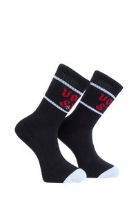 Chaussettes noires avec accents de couleur blanche au niveau des orteils et des bords côtelés, ornées de texte rouge et de détails en bordure blanche. Fabriquées en tissu extensible pour le confort.