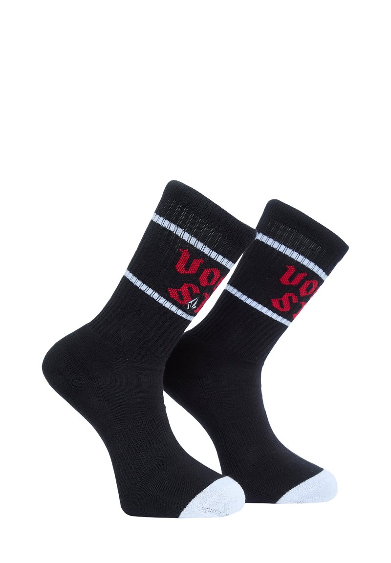 Chaussettes noires avec accents de couleur blanche au niveau des orteils et des bords côtelés, ornées de texte rouge et de détails en bordure blanche. Fabriquées en tissu extensible pour le confort.