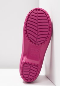 Suola di scarpa in gomma rosa brillante con motivo di presa testurizzato e logo circolare. Tacco e bordi lisci e arrotondati per comfort e stabilità.