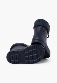 Paire de bottes de pluie en caoutchouc bleu marine, une droite et une sur le côté montrant la semelle texturée et le nom de la marque "igor".