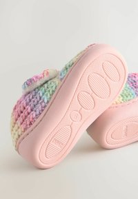 Chausson tissé multicolore avec une semelle en caoutchouc rose, présentant un fond texturé pour une bonne adhérence et un design doux et rembourré.