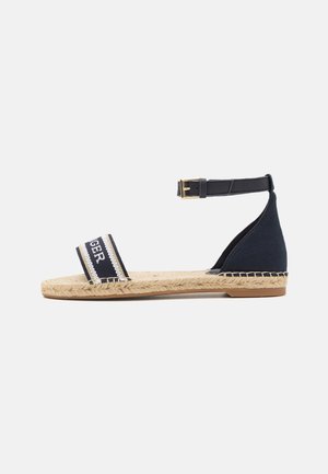 Sandalia espadrille marina con dos amplias correas de tela y hebilla en el tobillo. Suela envuelta en yute con una base plana de goma marrón.