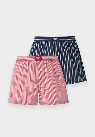 Δύο ζευγάρια ριγέ μποξεράκια, ένα μπλε ναυτικό με άσπρες ρίγες και ένα κόκκινο με άσπρες ρίγες, και τα δύο με τυπωμένες ζώνες μέσης.