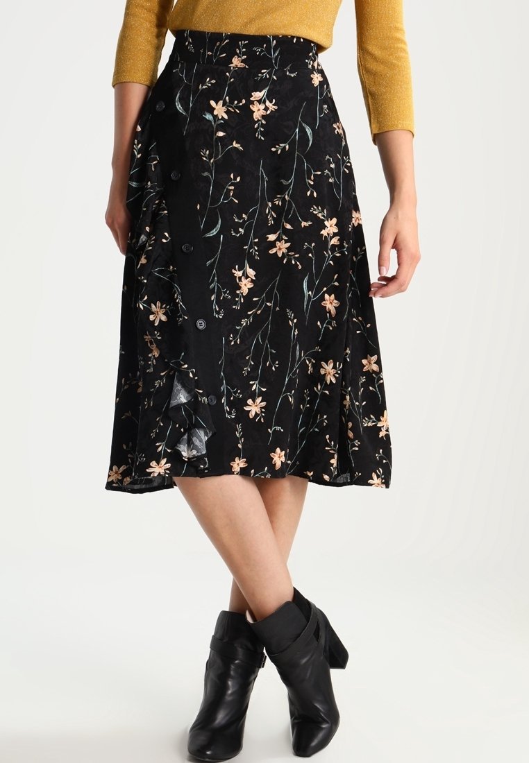 Jupe midi noire avec un motif floral, dotée de boutons sur le devant et d'un ourlet ondulé. Fabriquée en tissu léger avec une texture douce.