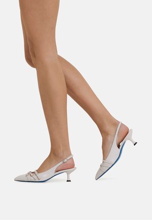 White leather slingback heels feature a pointed toe, curved heel, and decorative straps with a blue sole detail.