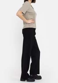 Beige geribbelde short-sleeve top met een kraagnek, gecombineerd met zwarte wijde broek en dikke zwarte platform schoenen.