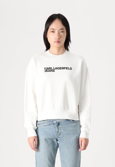 Бяла памучна суитчер с кръгло деколте, с черен текст "KARL LAGERFELD JEANS" на предната част. С широко покритие и ribbed маншети.
