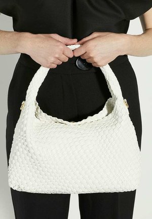 Sac en bandoulière tissé de couleur blanche en forme de croissant, avec une poignée tressée, mettant en avant des accents dorés et une surface texturée.