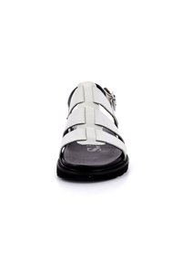 Sandalia de cuero blanca con un diseño de tiras cruzadas, suela negra, hebilla ajustable y una planta texturizada. Adecuada para uso casual.