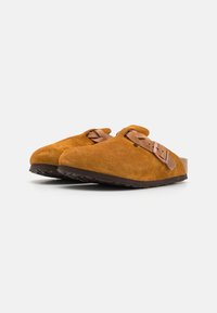 Suede tresko i sennepsgul med bred tåboks, justerbar brun læderrem og tekstureret mørk gummisål.