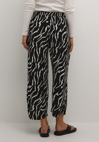 Black and white zebra print wide-leg pants with an elastic waistband, featuring a lightweight fabric and cropped hemline.