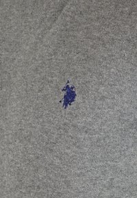 Graues gestricktes Poloshirt mit einem kleinen gestickten blauen Logo eines Pferdes und Reiters. Der Stoff hat eine glatte Textur mit einem dezenten Muster.