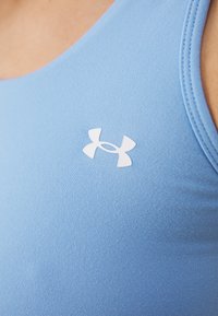 Top athletic senza maniche di un azzurro chiaro con una texture a coste e un logo Under Armour bianco ben visibile sul lato sinistro.