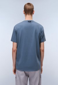 T-shirt en coton bleu avec une coupe décontractée, des manches courtes et un col rond ; texture lisse et détails de couture subtils à l'ourlet.
