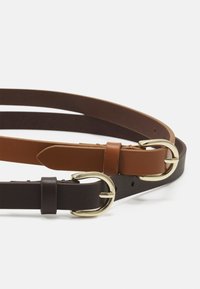 Bruine en donkerbruine leren riemen met goudkleurige metalen gespen, voorzien van een gladde textuur en meerdere gaten voor verstelbaarheid.