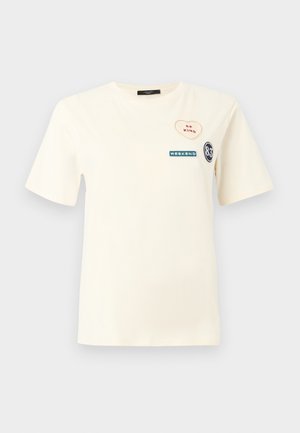 Kurzes cremefarbenes T-Shirt mit drei Aufnähern auf der Brust: Herz mit "BE KIND", Rechteck mit "WEEKEND" und Kreis mit "83".