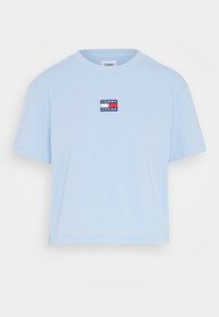 Ljusblå kortärmad t-shirt i bomull, med en liten broderad logotyp i röd, vit och blå på bröstet.