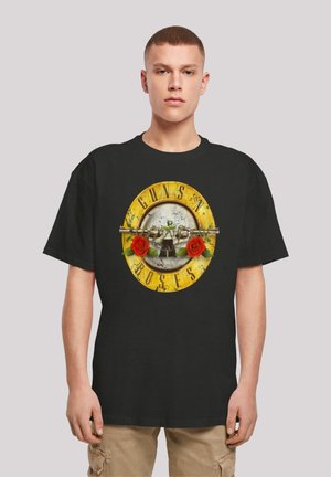 Black cotton t-shirt featuring a graphic design with roses, a skull, and a circular logo with "GUNS N' ROSES" in yellow letters.