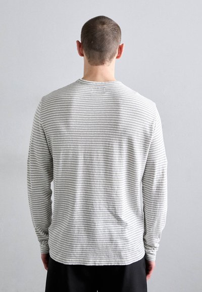 Camisa de mangas largas en gris claro con rayas horizontales en gris oscuro. Tejido suave, cuello redondo y ajuste relajado. Sin etiquetas ni logotipos visibles.