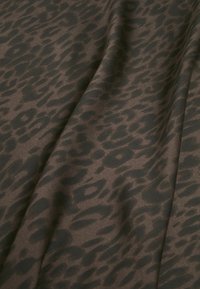 Hnědá látka s černým vzorem leopardího potisku, hladká textura, s mírným leskem a drapériemi, které vytvářejí hloubku.