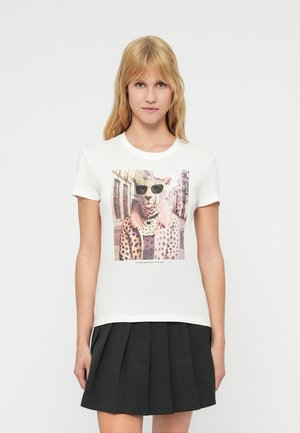 White cotton t-shirt featuring a printed graphic of a leopard in sunglasses. Short sleeves and a round neckline, paired with a black pleated skirt.