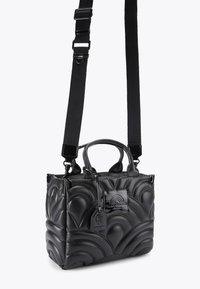 Borsa a tracolla nera trapuntata in pelle, con forma strutturata, manici superiori doppi e tracolla rimovibile. Etichette visibili sul davanti.