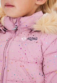 Rosa puffy-jacka med en krage av konstgjord päls, som har mönster av flerfärgad glittrig konfetti och en svart "ZIGZAG"-logotyp på framsidan.