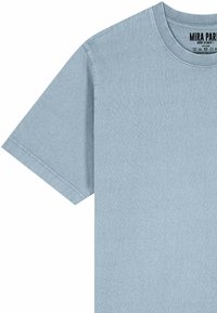 T-shirt di cotone azzurro chiaro con scollatura tonda e maniche corte. Presenta una texture morbida e un'etichetta con i dettagli del marchio all'interno del colletto.