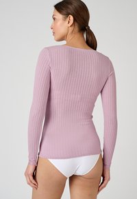 Top a maniche lunghe a coste rosa chiaro con scollo rotondo e tessuto testurizzato. L'orlo si allunga leggermente sul retro, presentando dettagli in pizzo ai polsini.