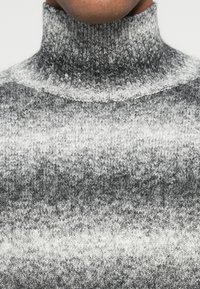 Szary sweter z wysokim kołnierzem, charakteryzujący się gradientowym wzorem w różnych odcieniach od ciemnoszarego do białego, wykonany z teksturowanej dzianiny.