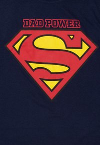 Maglietta blu navy con logo di Superman rosso e giallo e testo "DAD POWER" sopra in rosso. Tessuto di cotone morbido con design a girocollo.