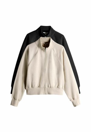 Sweatshirt sæt bestående af en cremet og en sort jakke. Begge har lynlås, høj krave, raglanærmer og ribbet kant. Blødt stof med en behagelig tekstur.