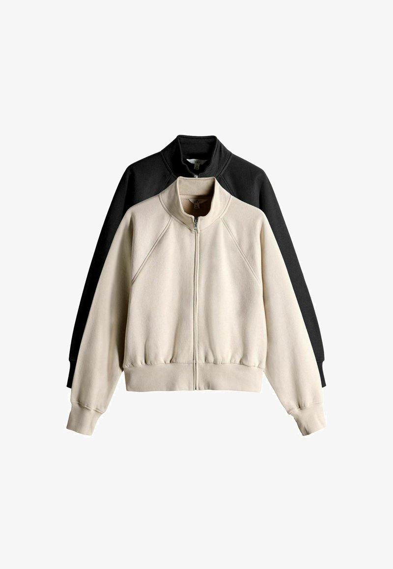 Conjunto de sudadera que incluye una chaqueta crema y una negra. Ambas tienen cierre de cremallera, cuello alto, mangas raglán y dobladillo de canalé. Tejido de textura suave.