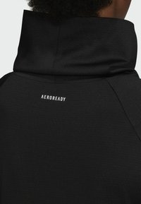 Gros plan du dos d'une personne portant un vêtement à capuche noir avec le mot "AEROREADY" imprimé en blanc près du centre supérieur.