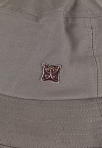 Gray fabric bucket hat featuring a textured surface, structured brim, and a metal star emblem with red accents stitched on the front.