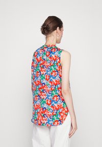 Top de tanque floral com um design multicolorido, apresentando flores vermelhas, azuis, verdes e brancas. Tecido suave com uma bainha assimétrica e costas plissadas.
