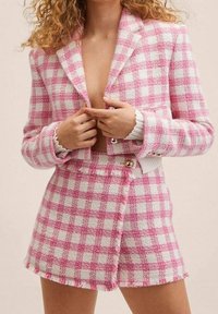 Roze-wit geruit blazer- en shortset, met een gestructureerde stof, rafelige randen en dubbele knoopsluiting op de blazer.