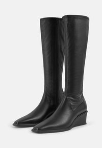 Bottes noires en cuir allant jusqu'au genou avec un bout pointu et un talon compensé. Elles disposent d'une fermeture éclair sur toute la longueur à l'arrière et d'une finition lisse.