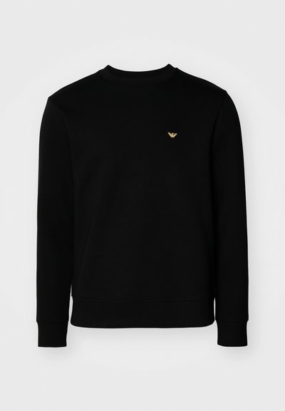 Black sweatshirt made of soft material, features a round neckline, long sleeves, and a small gold logo on the chest.