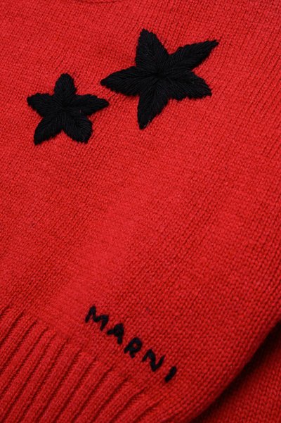 Rød strikket genser med svarte broderte blomster og "MARNI"-logo nederst. Teksturen er myk med ribbede mansjetter.