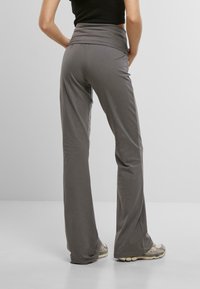 Pantaloni grigi svasati con una cintura ampia. Realizzati in un materiale morbido ed elasticizzato. Il design presenta una texture liscia e una vestibilità comoda.