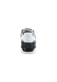 Sneaker a motivi bianco e nero con suola piatta, tacco pronunciato e marchio "GUESS" sul retro. Materiali lisci e testurizzati utilizzati.