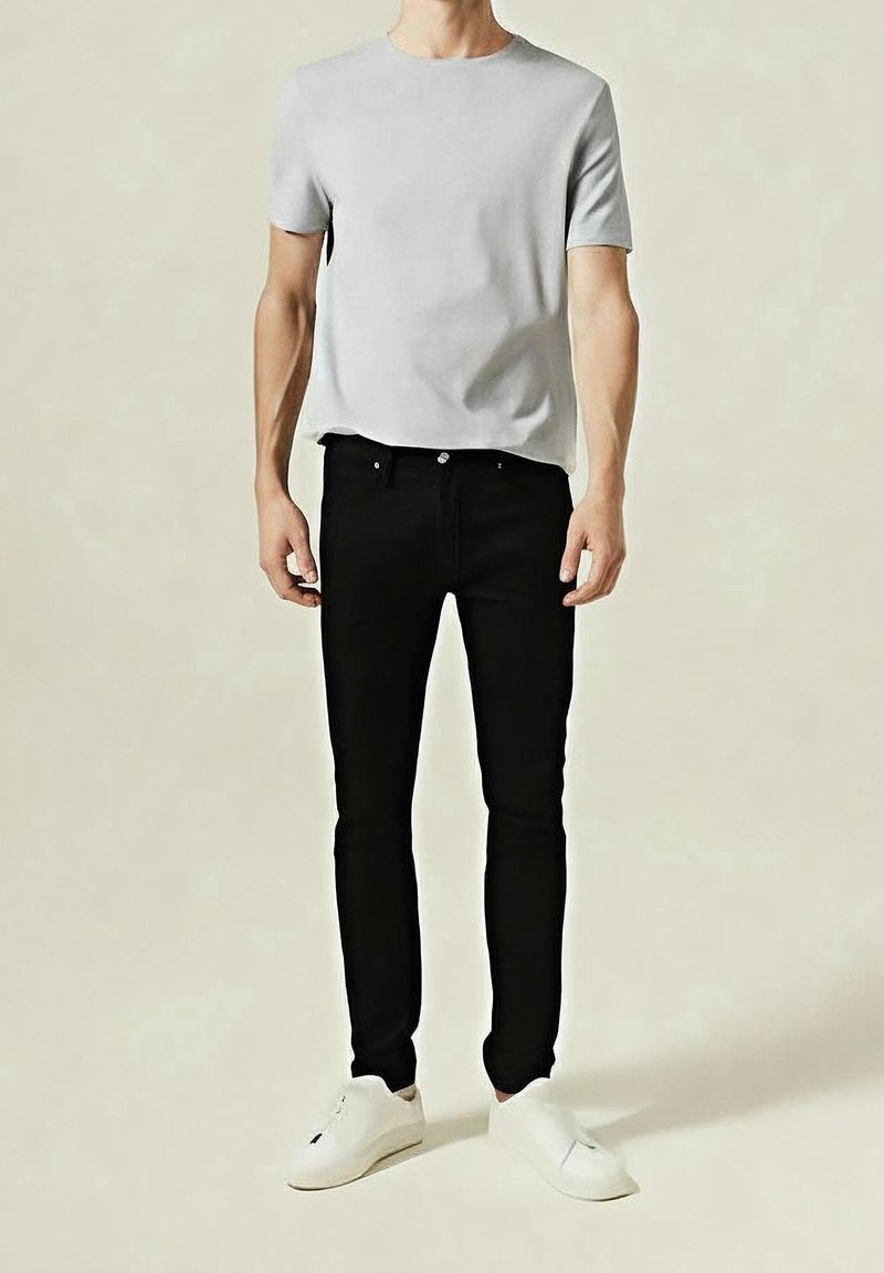 Šedé tričko s krátkým rukávem, černé úzké džíny a bílé tenisky; minimalistický design s čistými liniemi a bez viditelných vzorů či log.