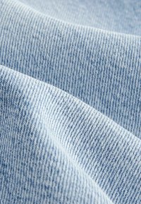 Heledad sinine denim kangas sujuva tekstuuriga, millel on diagonaalne twill-kootud mustri ja värvi peened variatsioonid sügavuse jaoks.