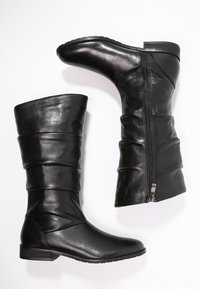 Bottes noires en cuir jusqu'au genou avec un design plissé, une fermeture éclair sur le côté, des semelles plates et une texture lisse.
