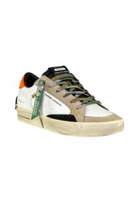 Sneaker bianco con accenti in suede beige e nero, lacci mimetici e una piccola linguetta arancione sul tallone. Presenta una suola testurizzata e consumata.
