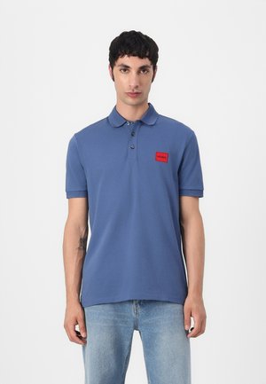 Plava polo majica od pamuka, s tri gumba, rebrastim ovratnikom i crvenim logotipom "HUGO" na lijevoj strani prsnog koša.