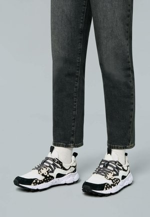 Sneaker nero e bianco con design testurizzato, dotate di una suola maculata, lacci frontali, e una combinazione di materiali tra cui rete e camoscio.